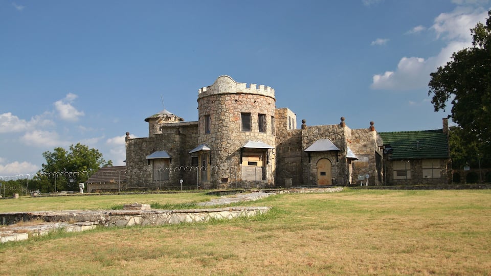 A historic stone building with a turret and multiple windows.