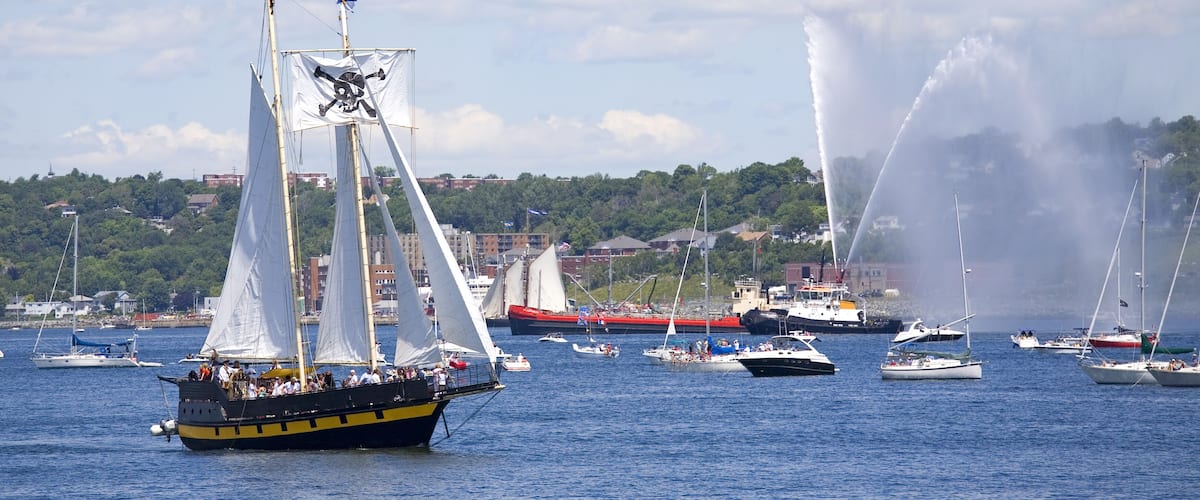 A tall ship is saluted with water cannons as she sails out of Halifax Harbour with Dartmouth in the background during the sail past of the Nova Scotia Tall Ships Festival 2009