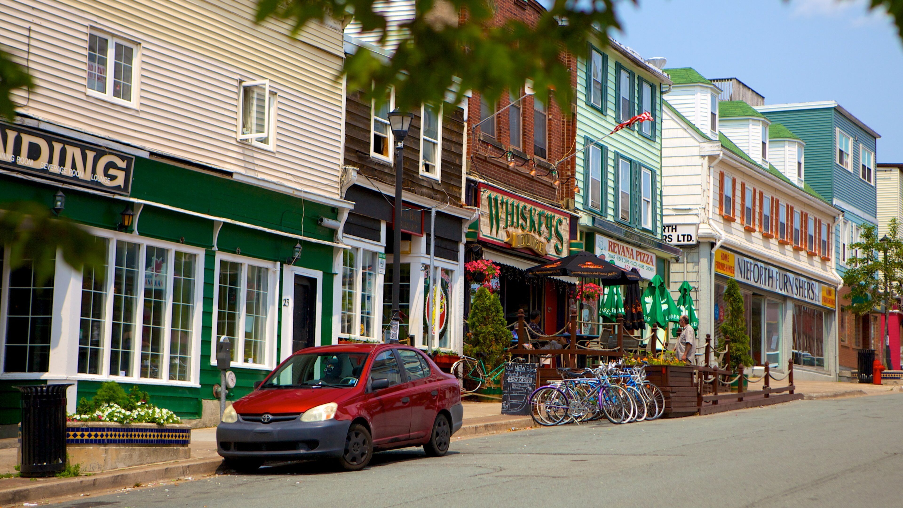 A street lined with colorful buildings, including a whiskey lounge and a furniture store.