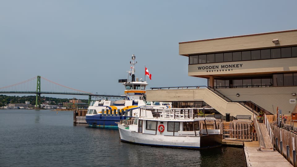 A ferry docked at a pier with a bridge in the background and a building labeled "Wooden Monkey Restaurant".