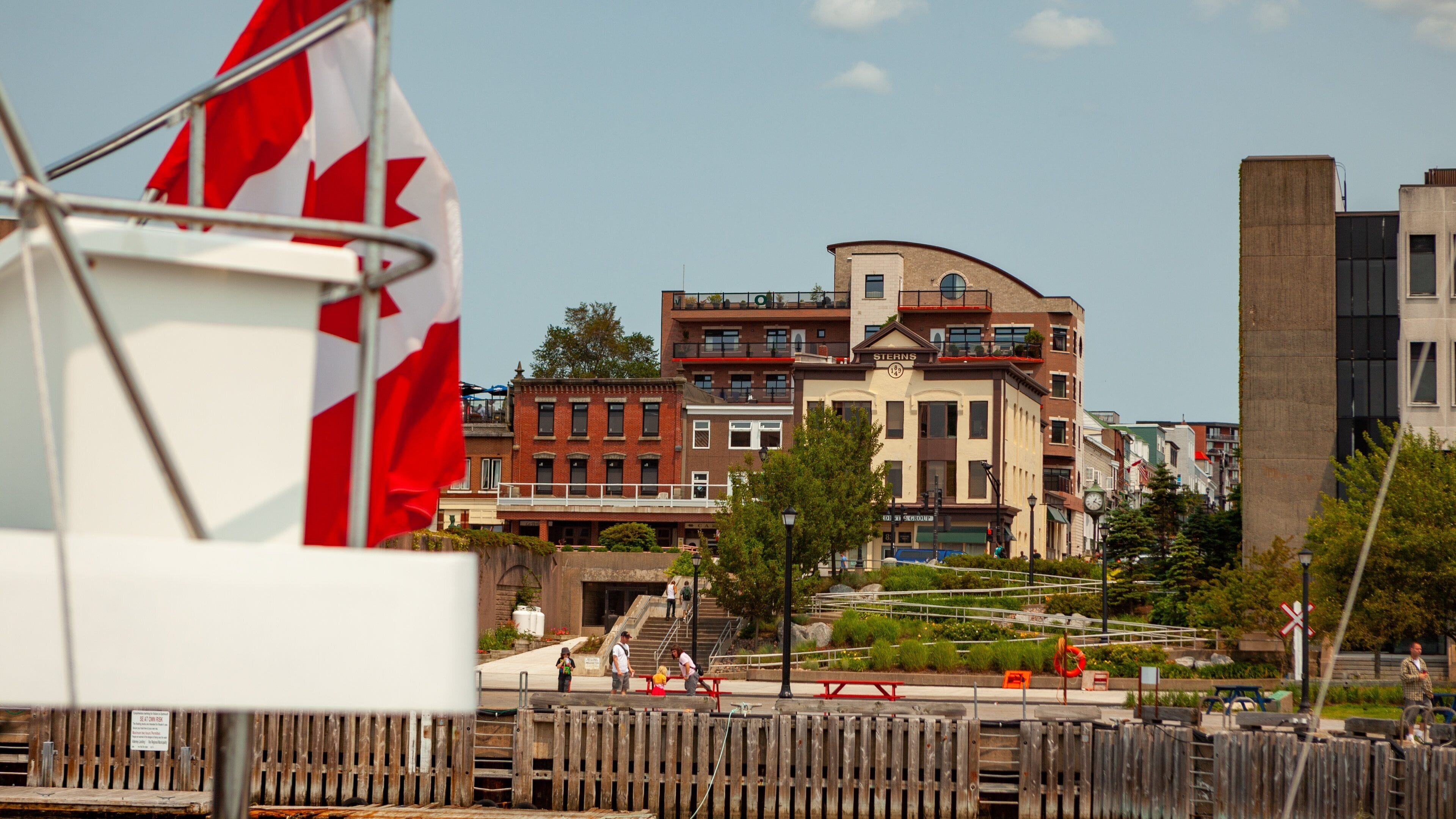 A waterfront with buildings, a flag, and a wooden fence.