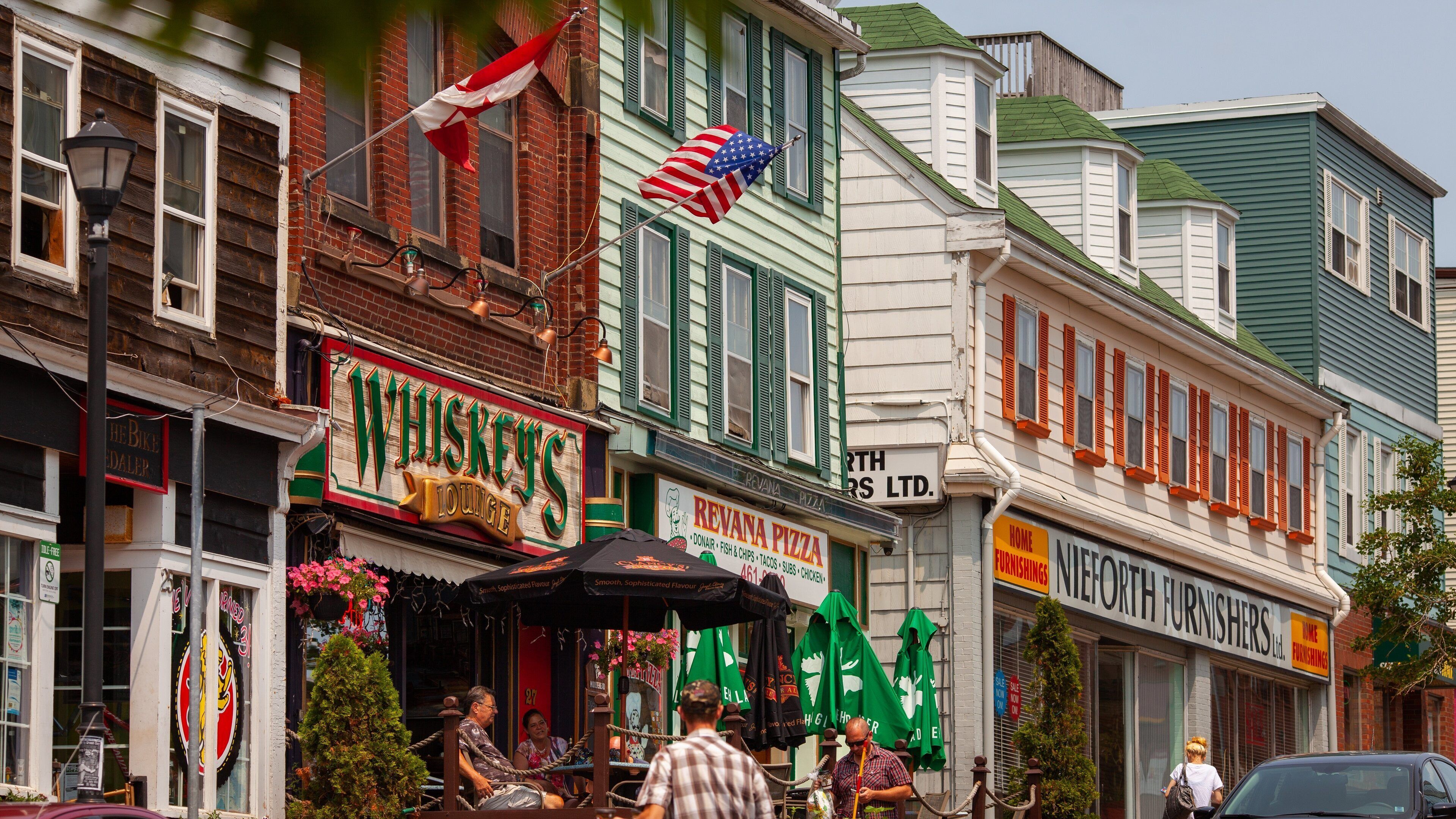 A street with various shops including a whiskey lounge, a pizza restaurant, and a furniture store.