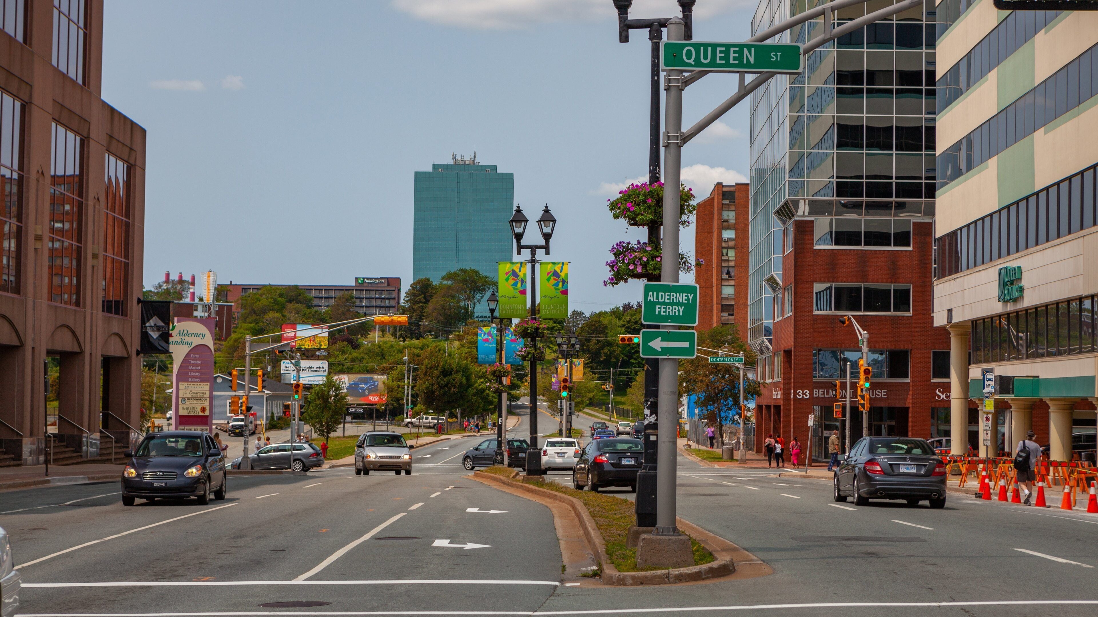 A city street with cars, buildings, and street signs.