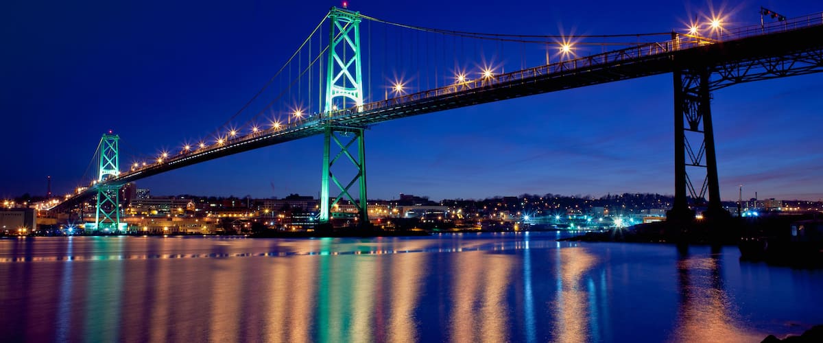 A brightly lit bridge at night with its lights reflecting on the water.