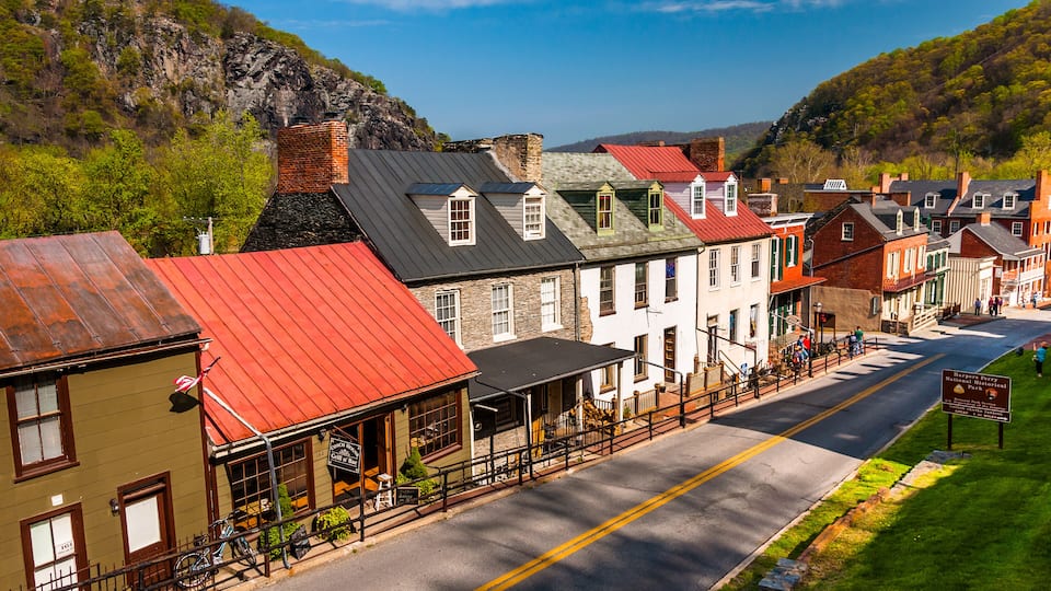 A historic town with red-roofed buildings, a paved street, and a mountainous backdrop.