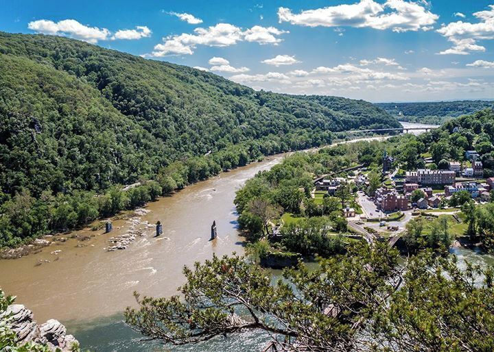 A river winding through a town surrounded by forested hills.