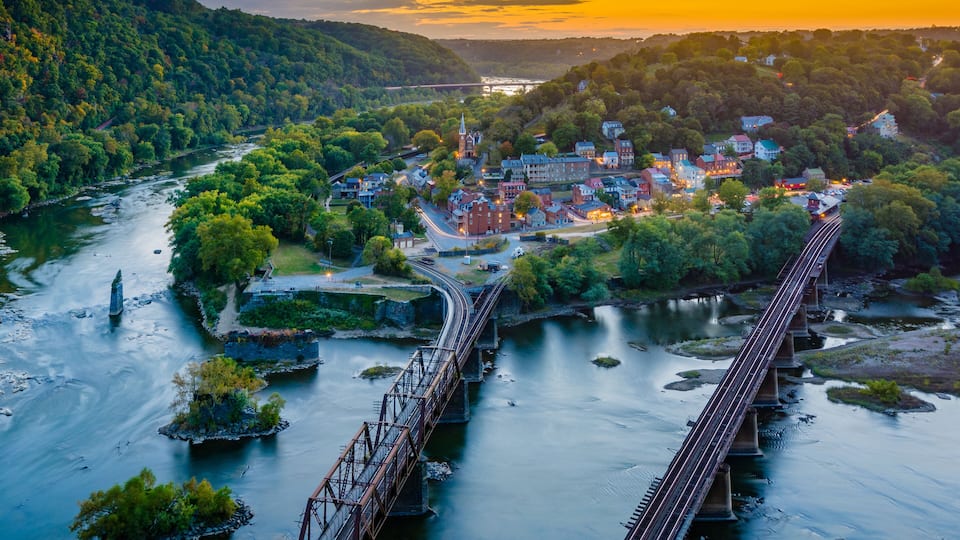 A river with a bridge, a town with buildings, and a forested hillside.