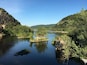 Un río bordeado por colinas verdes y un puente.