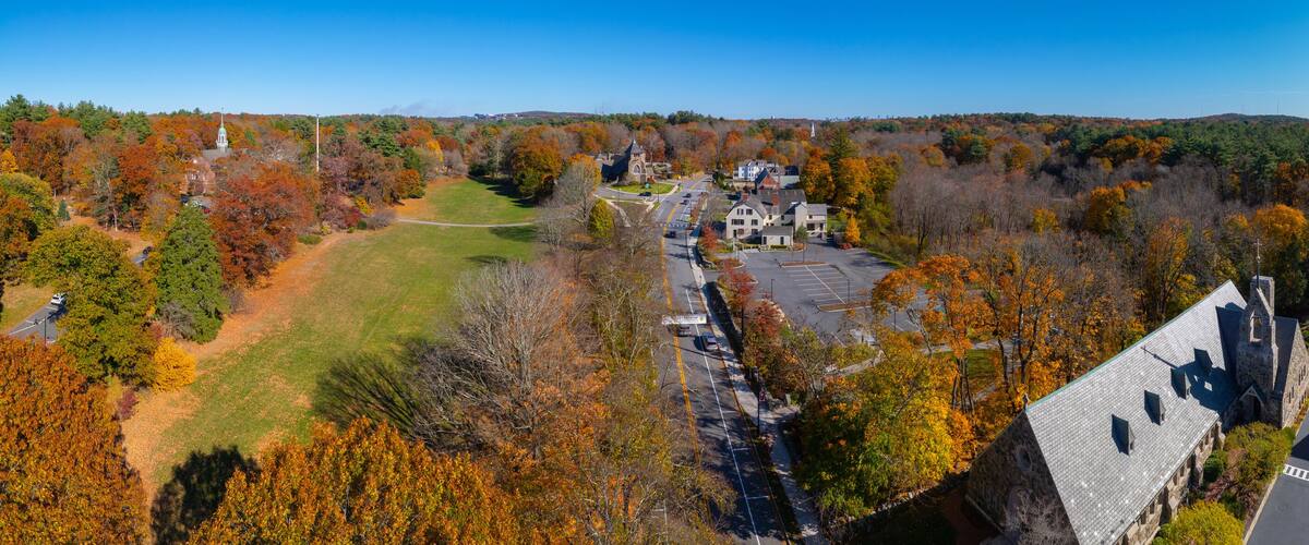 An aerial view of a town with autumn foliage, a church, and a park.
