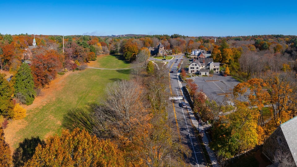 An aerial view of a town with autumn foliage, a church, and a park.