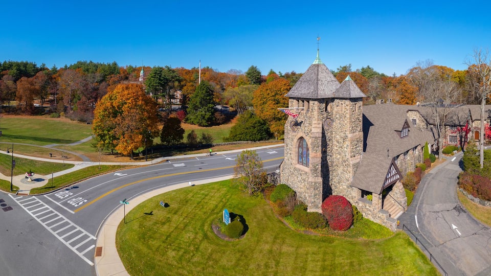 A roundabout with a stone tower, autumn trees, and residential houses.