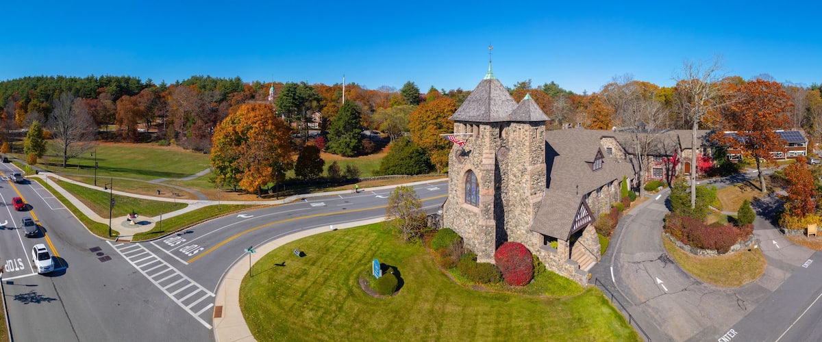 A roundabout with a stone tower, autumn trees, and residential houses.