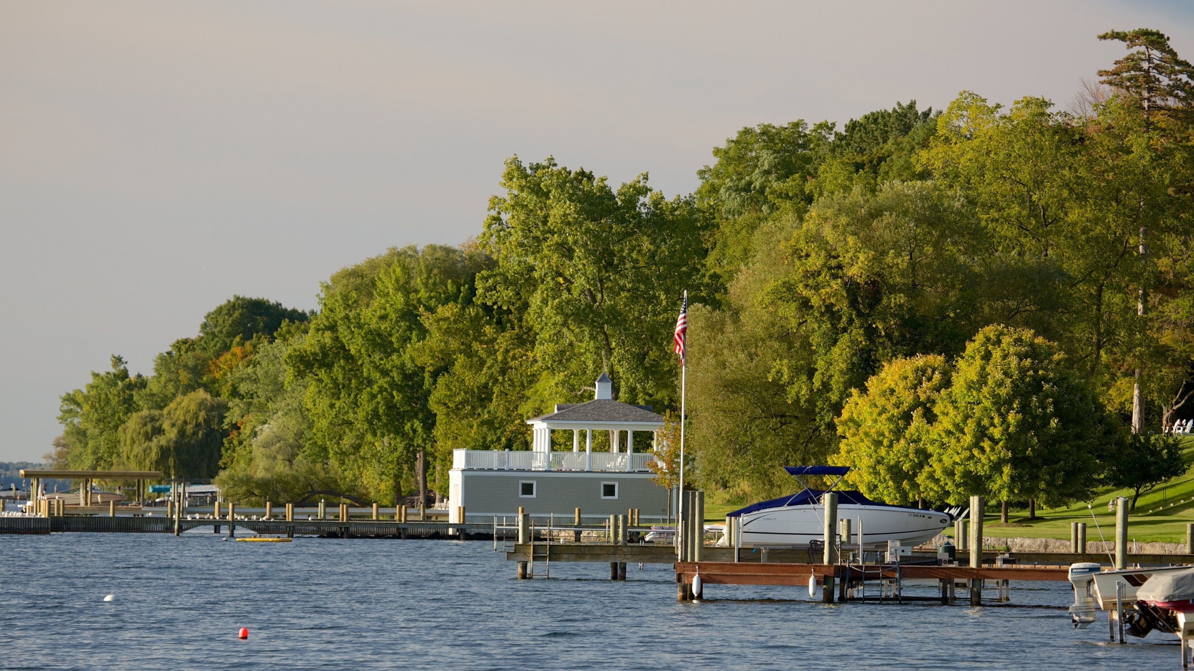 A dock with a gazebo, a boat, and a forested hillside.