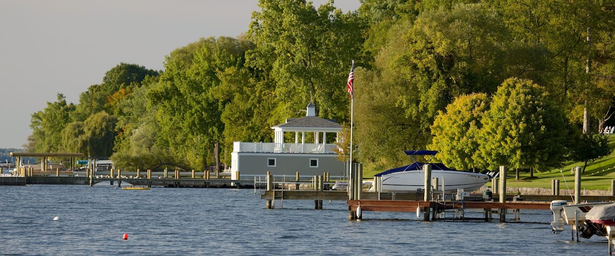 A dock with a gazebo, a boat, and a forested hillside.