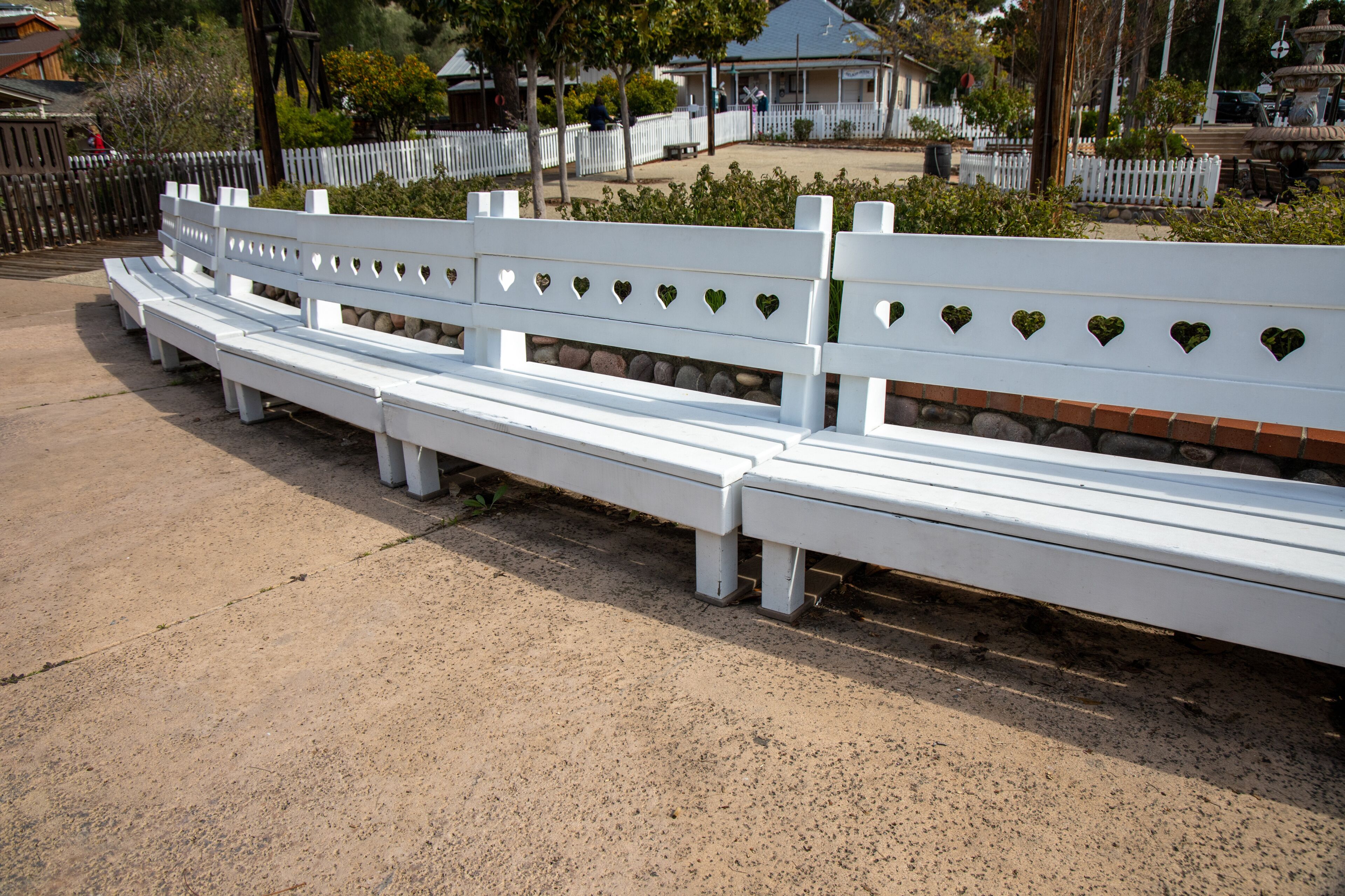 The white benches by the water fountain at the Old Poway Park in Poway, California.
