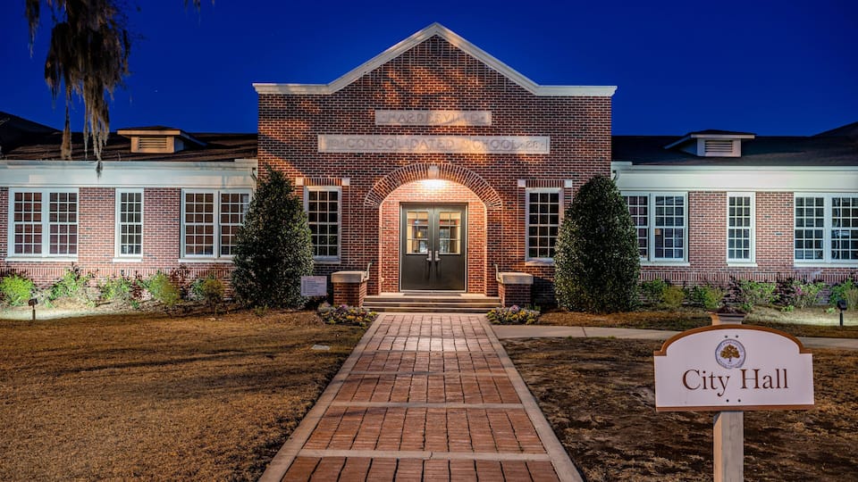 A brick building with a sign reading 'City Hall' in front.