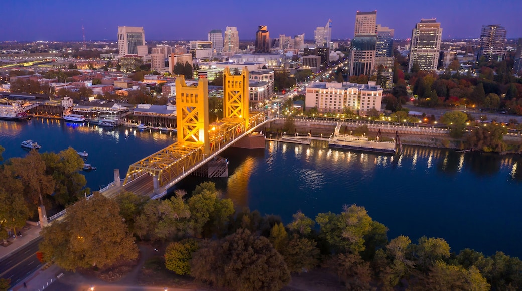 Evening view of the iconic Sacramento, CA, Bridge, illuminated at dusk. City skyline and riverfront are visible. Tower Bridge, Sacramento, California, USA