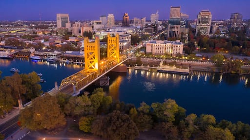 Evening view of the iconic Sacramento, CA, Bridge, illuminated at dusk. City skyline and riverfront are visible. Tower Bridge, Sacramento, California, USA