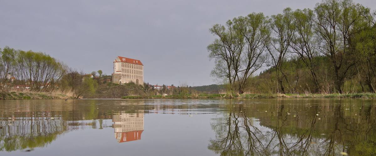 Historical Plumlov castle from 17th century and reflection on the surface of the pond in Prostejov district in Czech republic. Cloudy smoke fog air pollution sky.