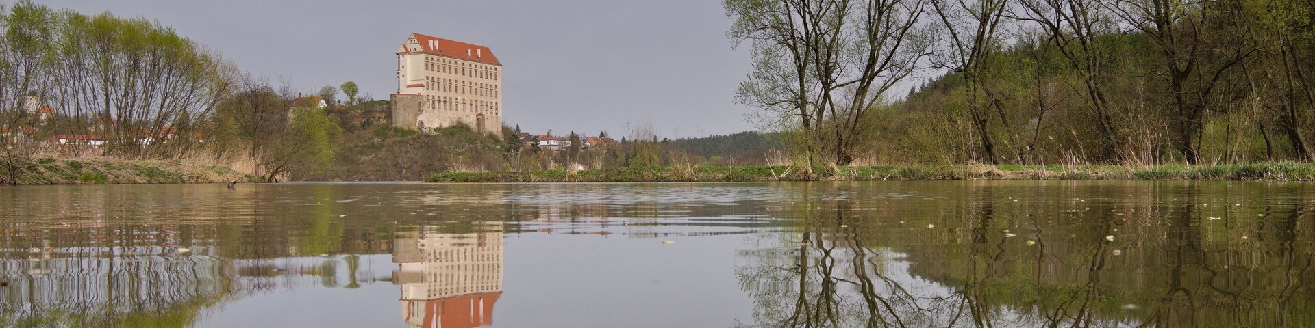 Historical Plumlov castle from 17th century and reflection on the surface of the pond in Prostejov district in Czech republic. Cloudy smoke fog air pollution sky.