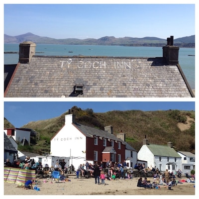 A coastal scene with a building labeled 'TY COCH INN' and a beach area with people and a colorful striped canopy.