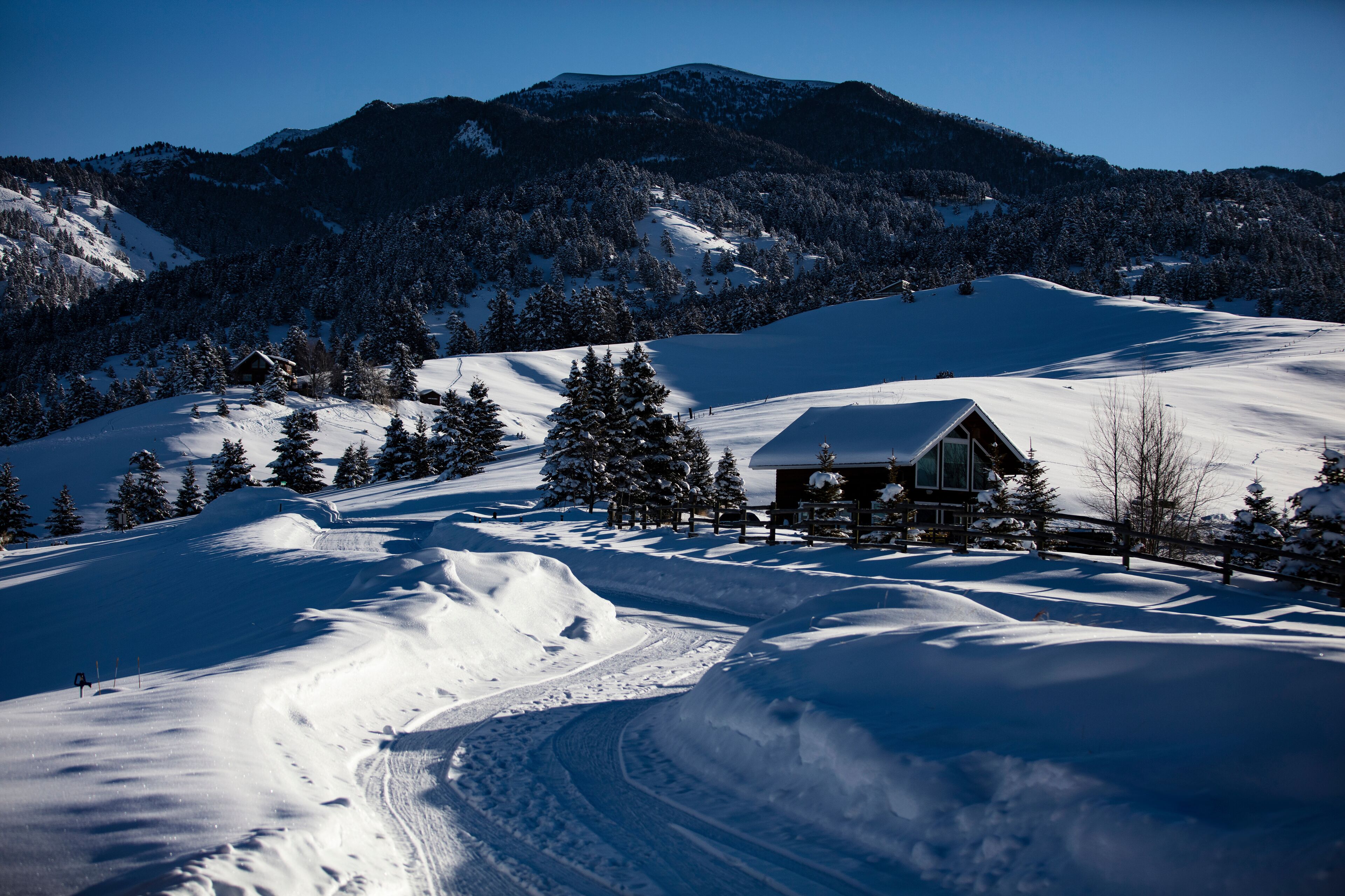 A snow-covered mountain landscape with a cabin and a ski trail.