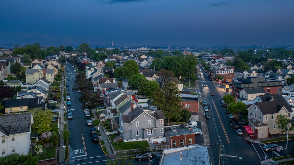 A residential area with houses, streets, and a distant city skyline.