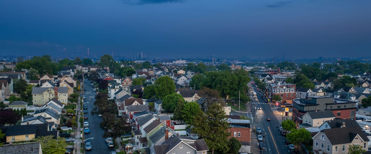 A residential area with houses, streets, and a distant city skyline.