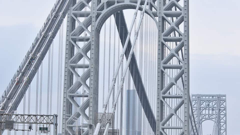 A large suspension bridge with a complex steel framework and multiple lanes for traffic.
