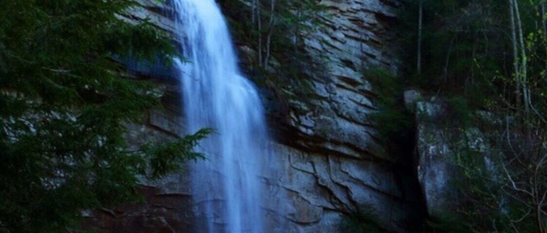 A waterfall cascading down a rocky cliff surrounded by dense forest.