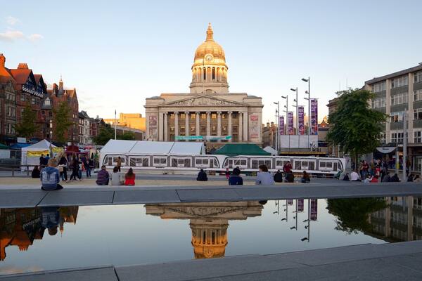 A historic building with a dome, a reflection pool, and surrounding modern buildings.