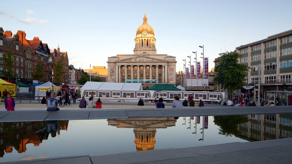 A historic building with a dome, a reflection pool, and surrounding modern buildings.