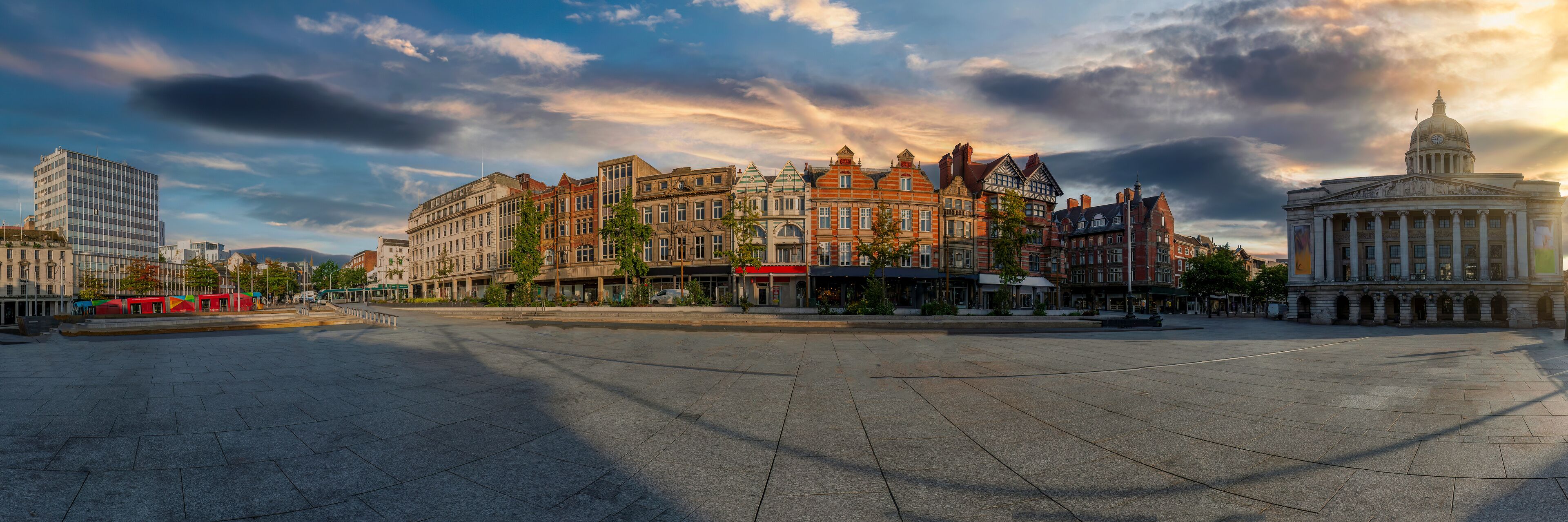 A wide city square with historic buildings, a tram, and a large government building.