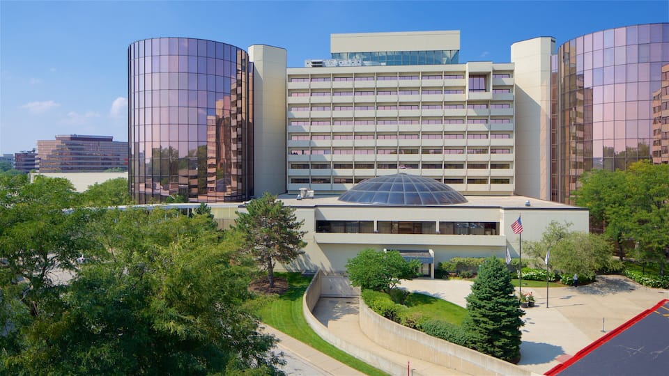 A modern building with a glass dome, surrounded by trees and other buildings.