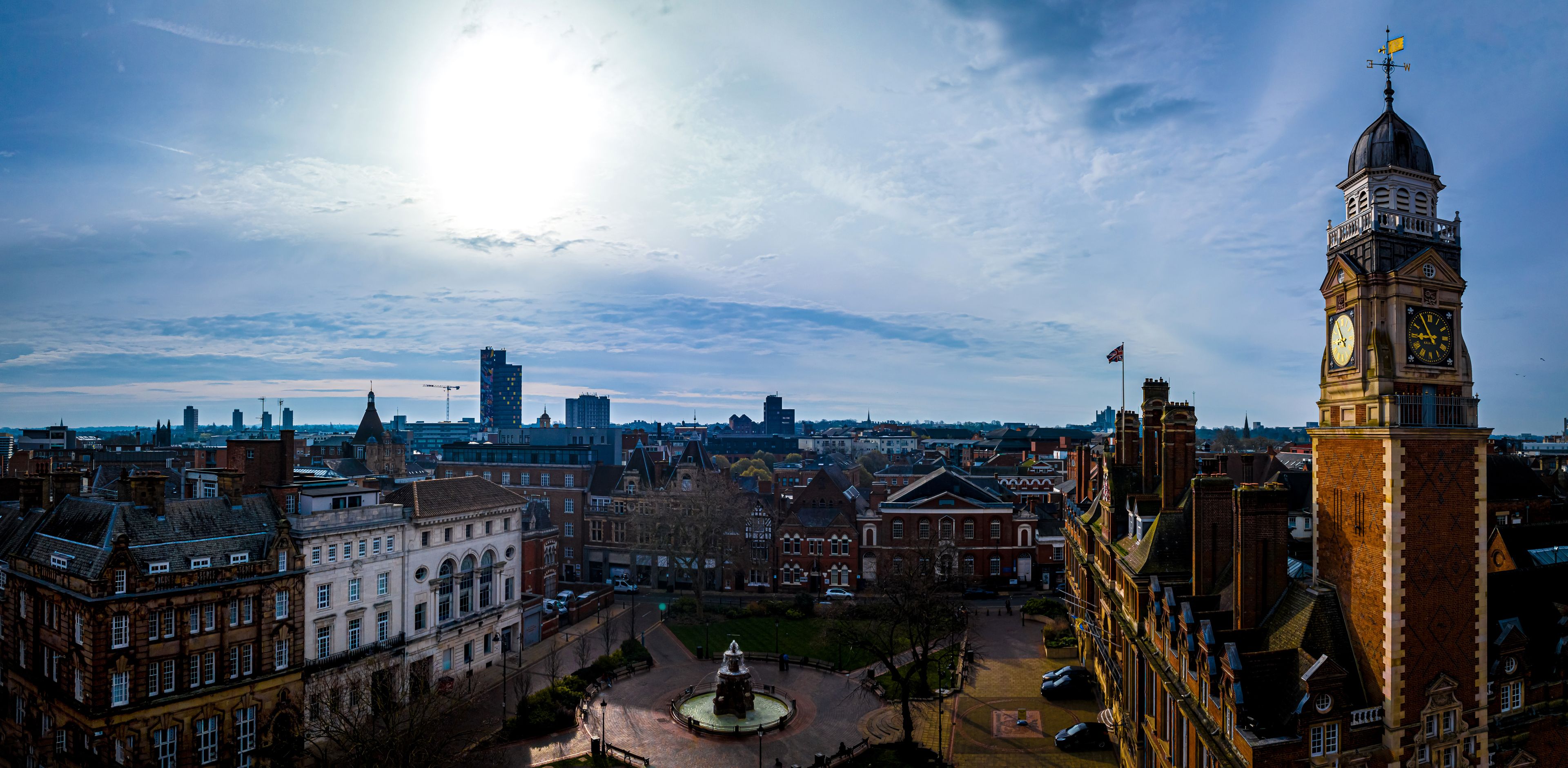 A cityscape with a prominent clock tower, historic buildings, and a clear sky.