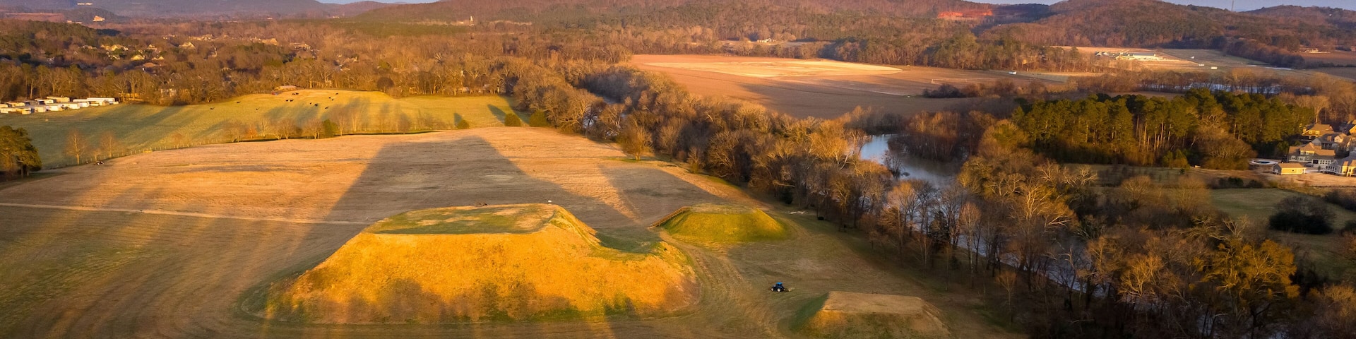 A rural landscape with rolling hills, fields, and a river.