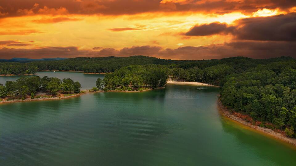 A river winding through a forested landscape with a beach on one side.