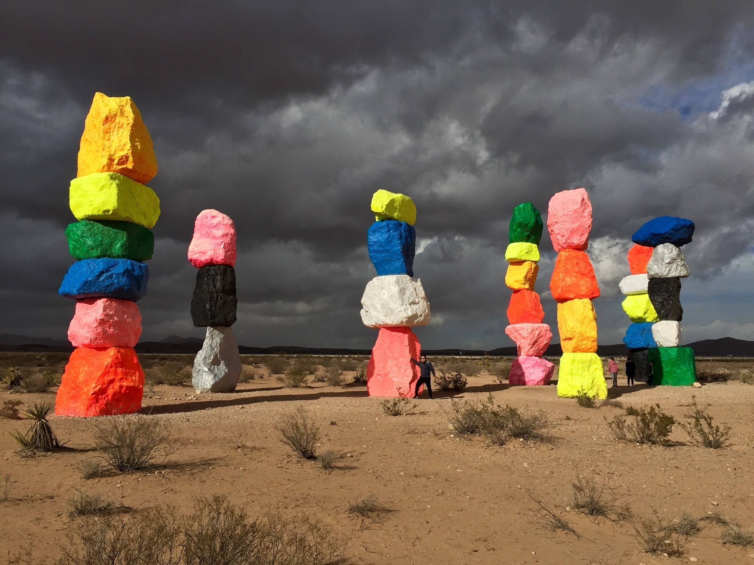 Colorful rock stacks in a desert landscape with a cloudy sky.