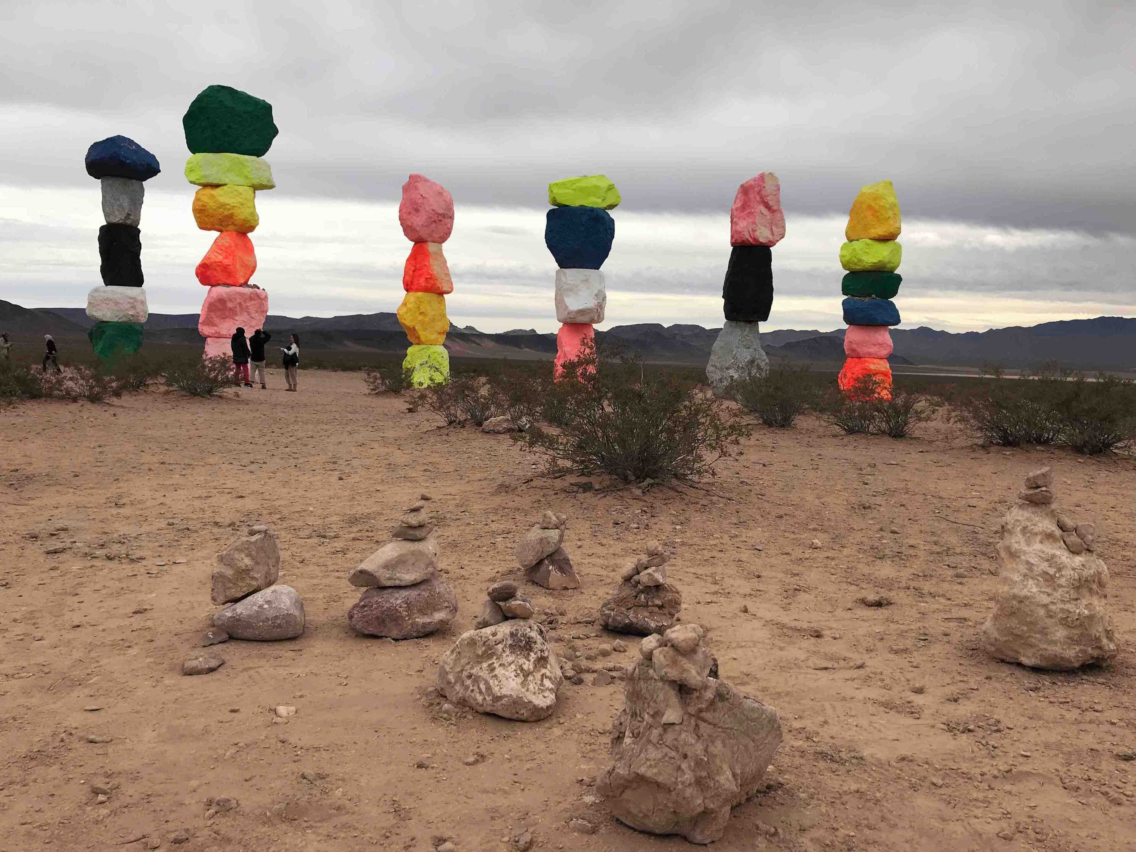 A desert landscape with colorful rock stacks and a group of people in the background.