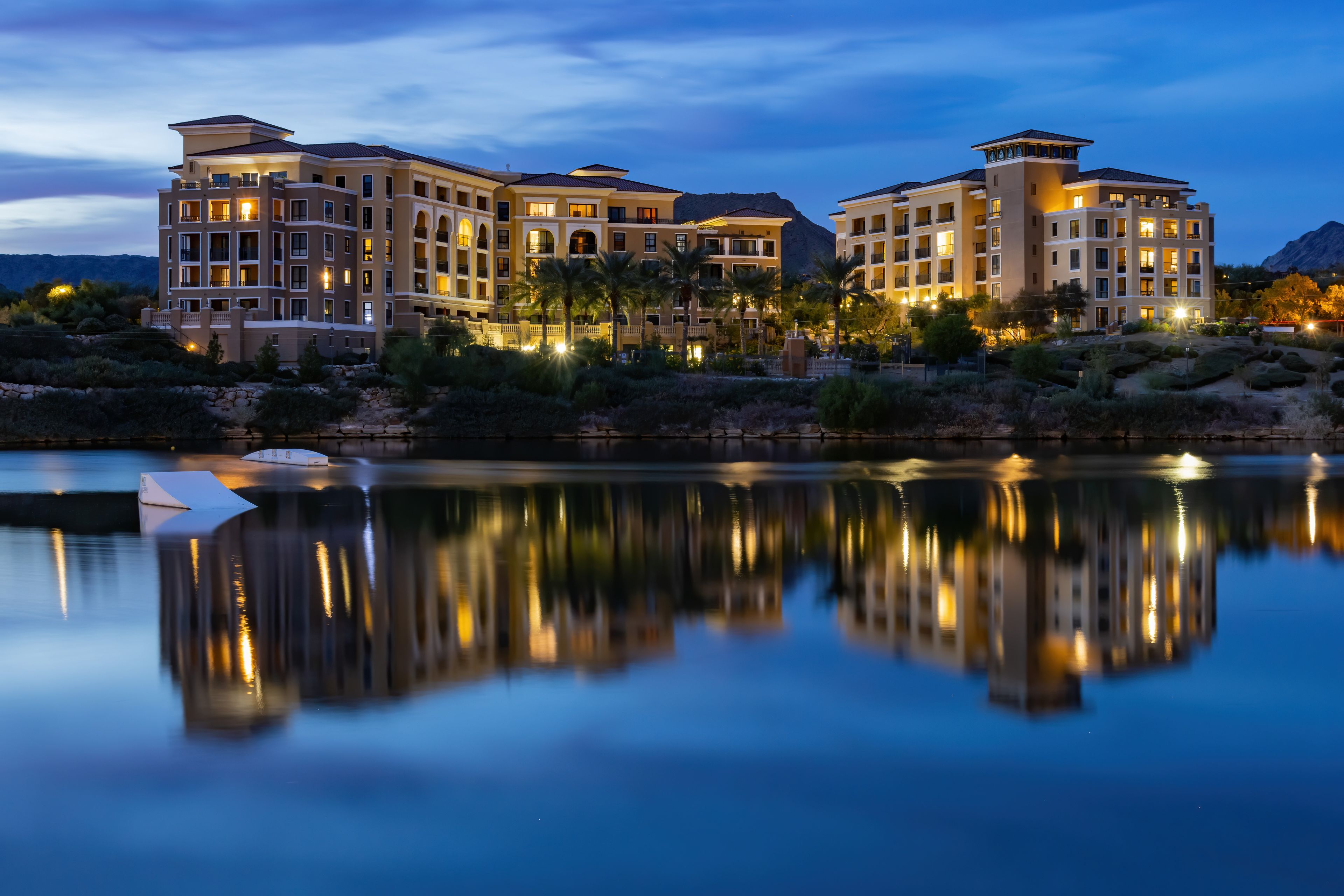 A multi-story resort with a reflective pool in the foreground.