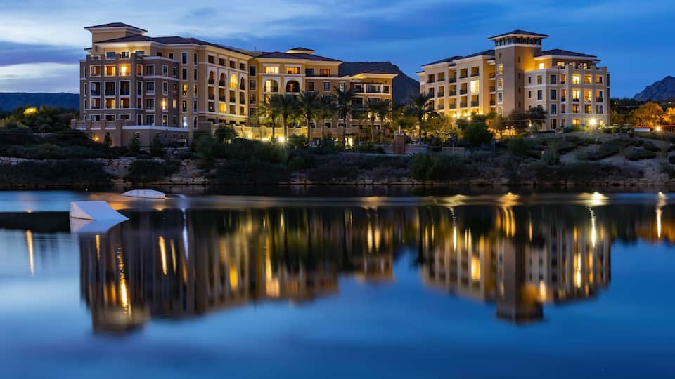 A multi-story resort with a reflective pool in the foreground.
