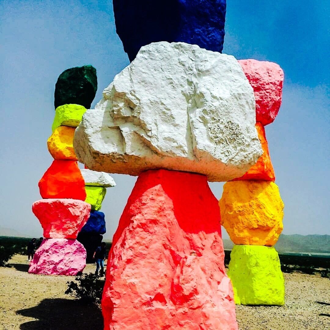 Colorful stacked rocks with a clear blue sky in the background.
