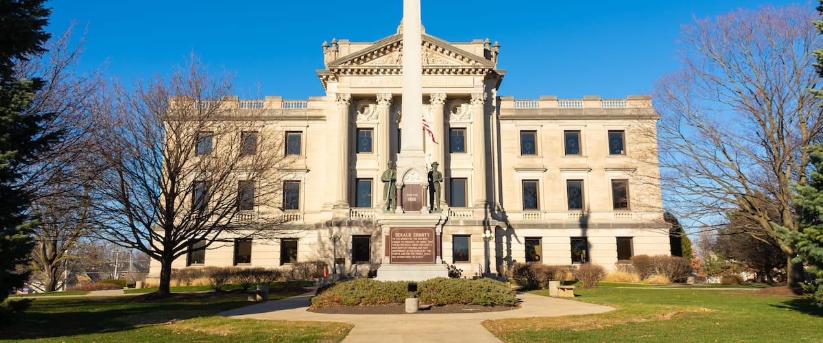 A stately building with a central column, a statue, and a plaque.