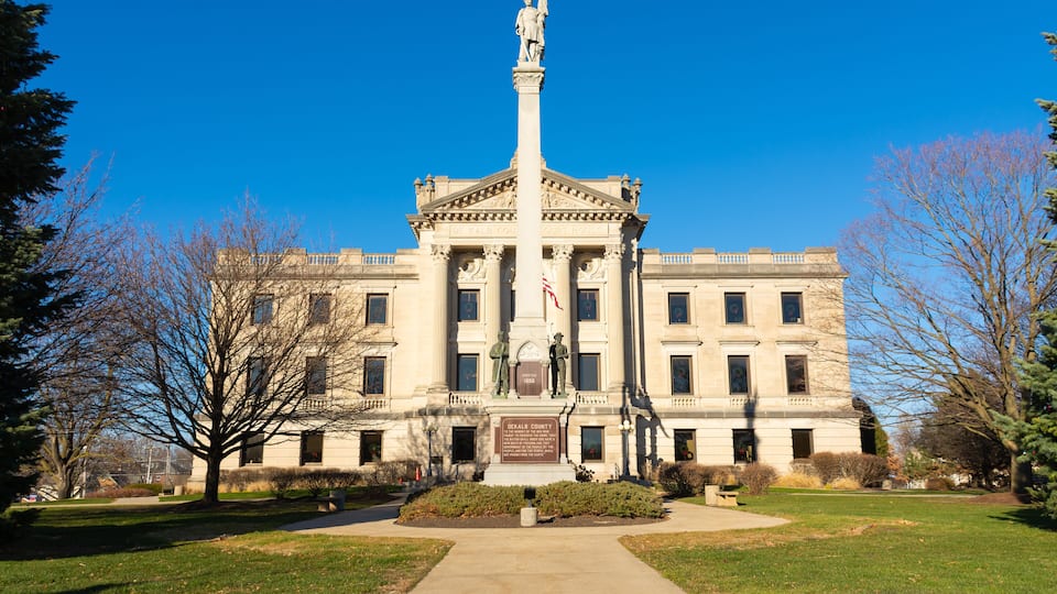 A stately building with a central column, a statue, and a plaque.
