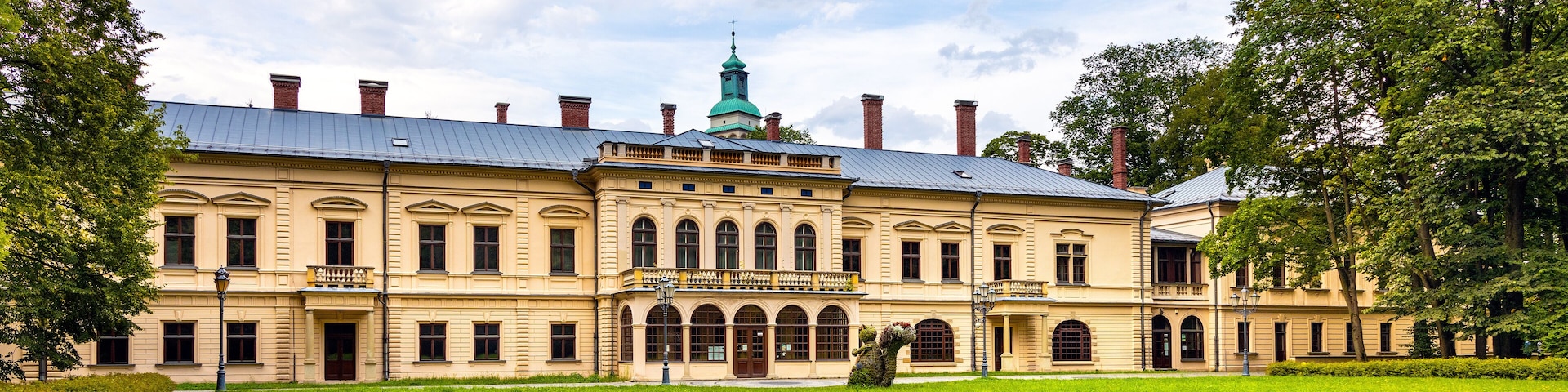 A large, historic building with a green dome and multiple chimneys.