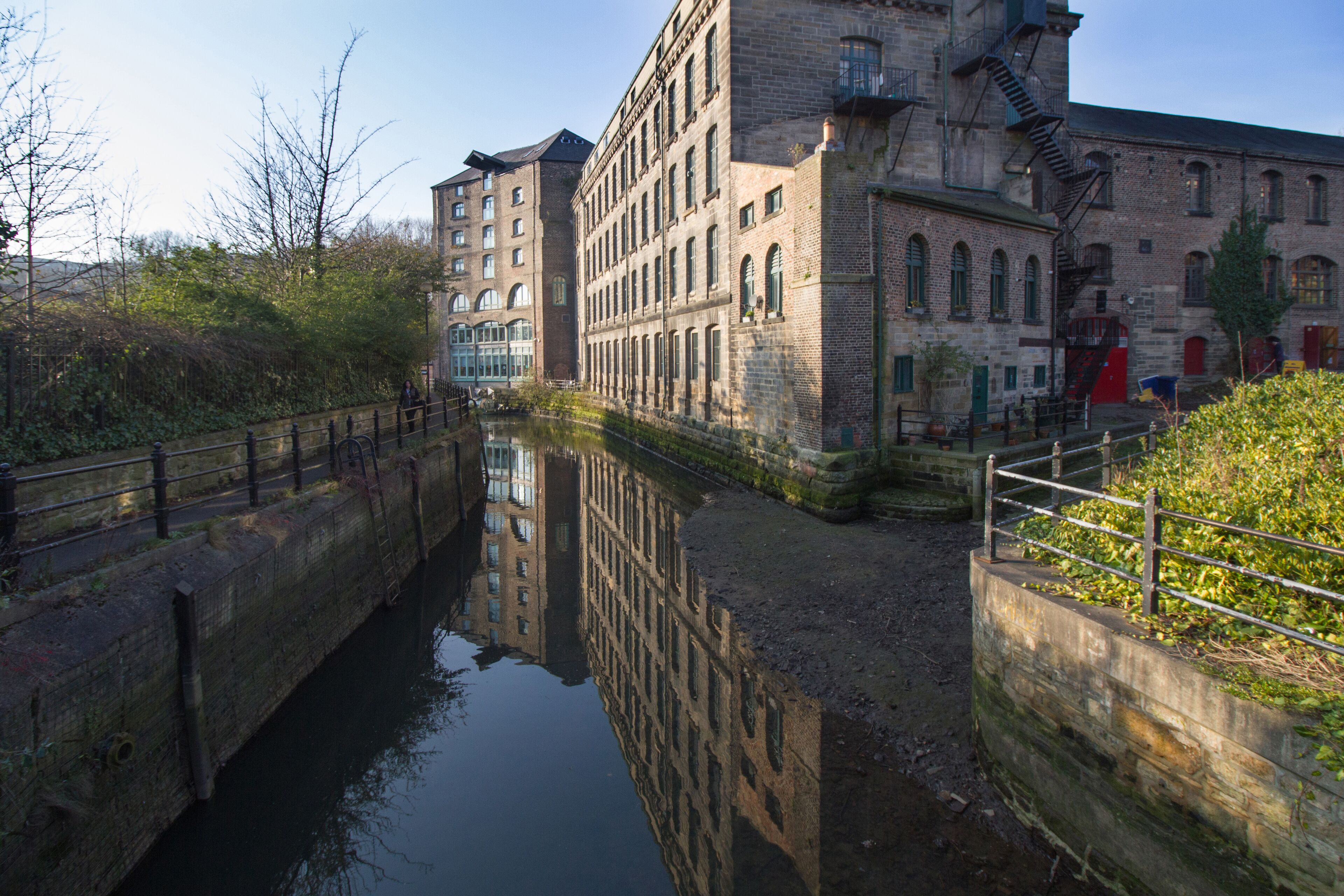 Old converted warehouse reflected on to the river in Ouseburn area of Newcastle Upon Tyne