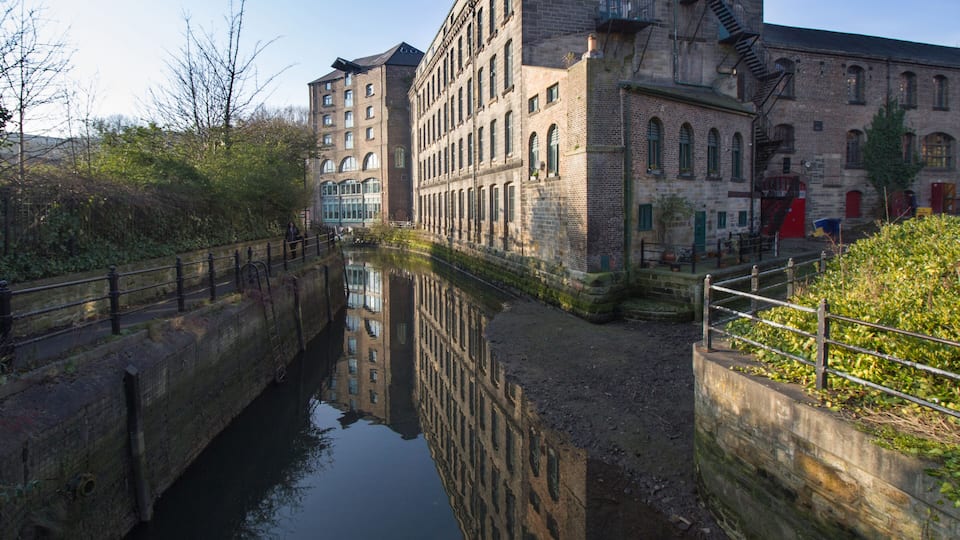 Old converted warehouse reflected on to the river in Ouseburn area of Newcastle Upon Tyne