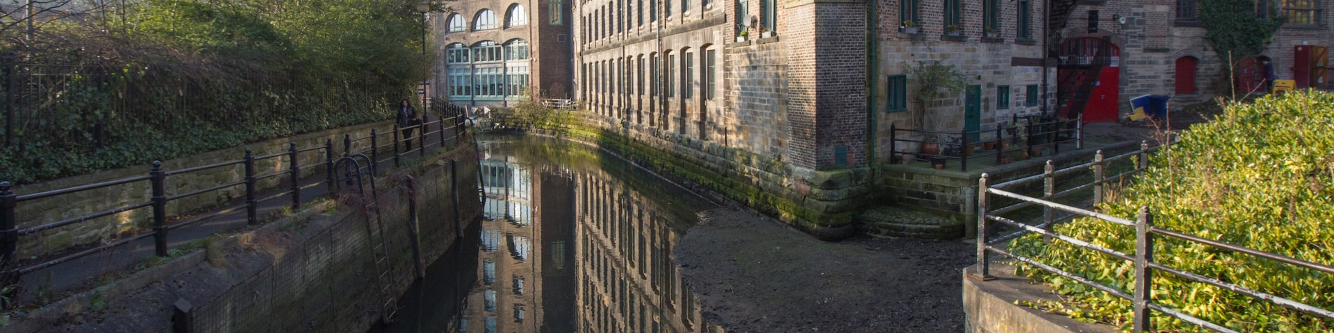 Old converted warehouse reflected on to the river in Ouseburn area of Newcastle Upon Tyne