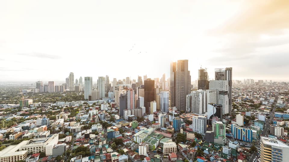 Makati, Metro Manila, Philippines - The Makati skyline as seen from Mandaluyong. Intense sun glare and dramatic urban shot.