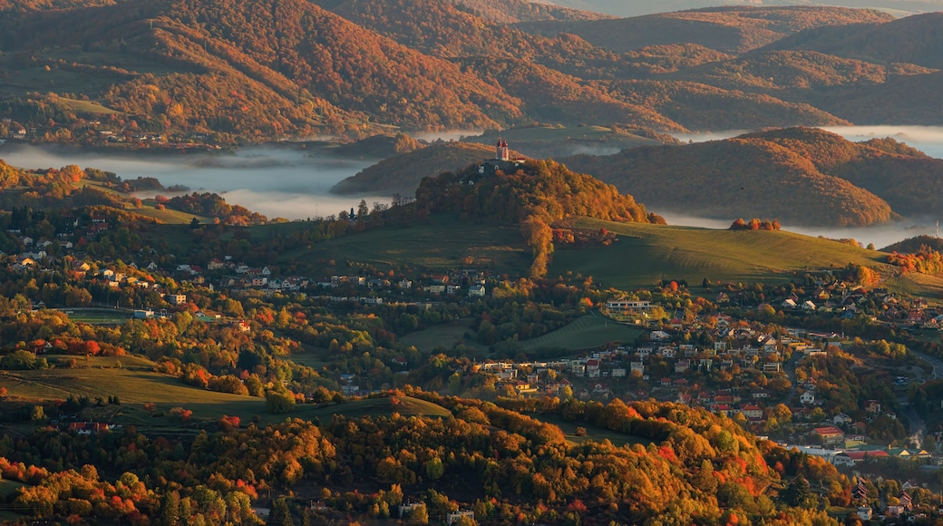 Beautiful autumn landscape of a church on a hill, autumn fog in the valleys. Idyllic scenery from a bird's eye view of the picturesque town of Banska Stiavnica